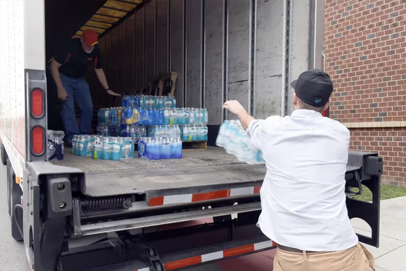 Men unloading water from truck