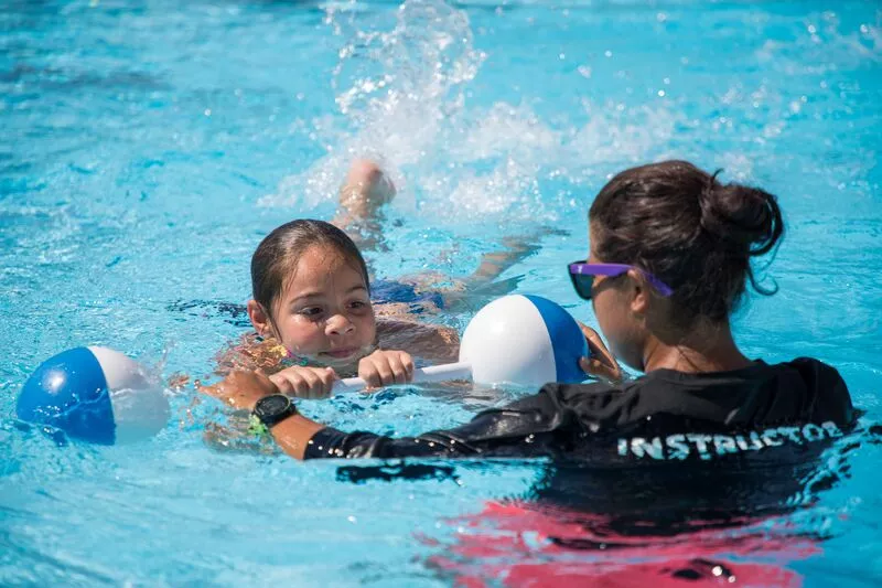 Young woman giving swimming lessons at outside pool at YMCA