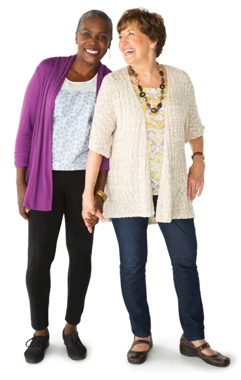 Two middle aged women standing close and laughing